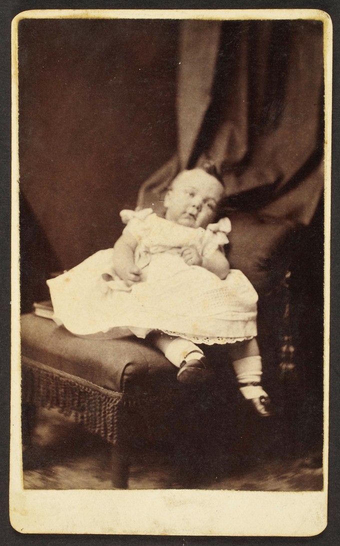 Unknown sitter [portrait of infant on upholstered armchair]