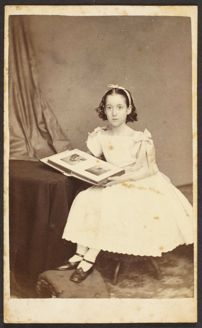 Unknown sitter [Portrait of a seated girl posed with a cabinet card album]
