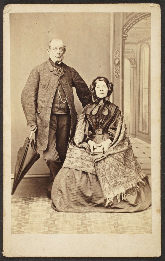 Unknown sitters [portrait of a standing man holding an umbrella next to a seated  woman holding a book]