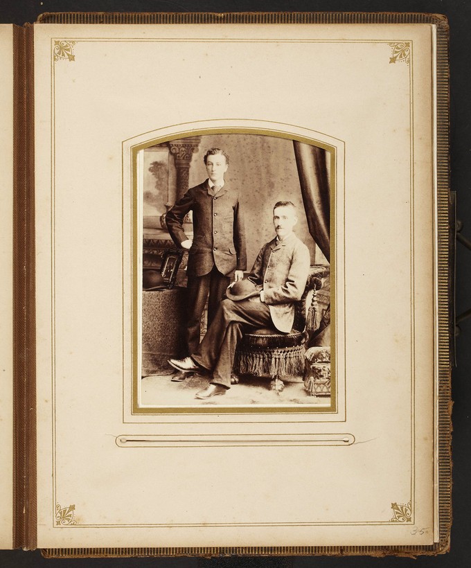 Unknown sitters [portrait of standing man and a seated man with hat on lap]